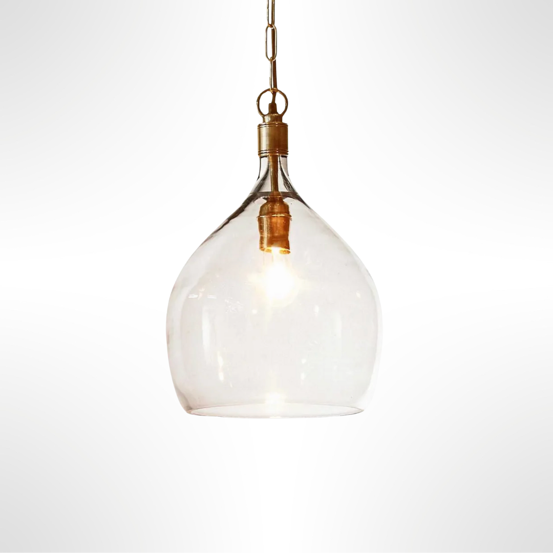 Clear glass pendant light with brass fixture on a white background
