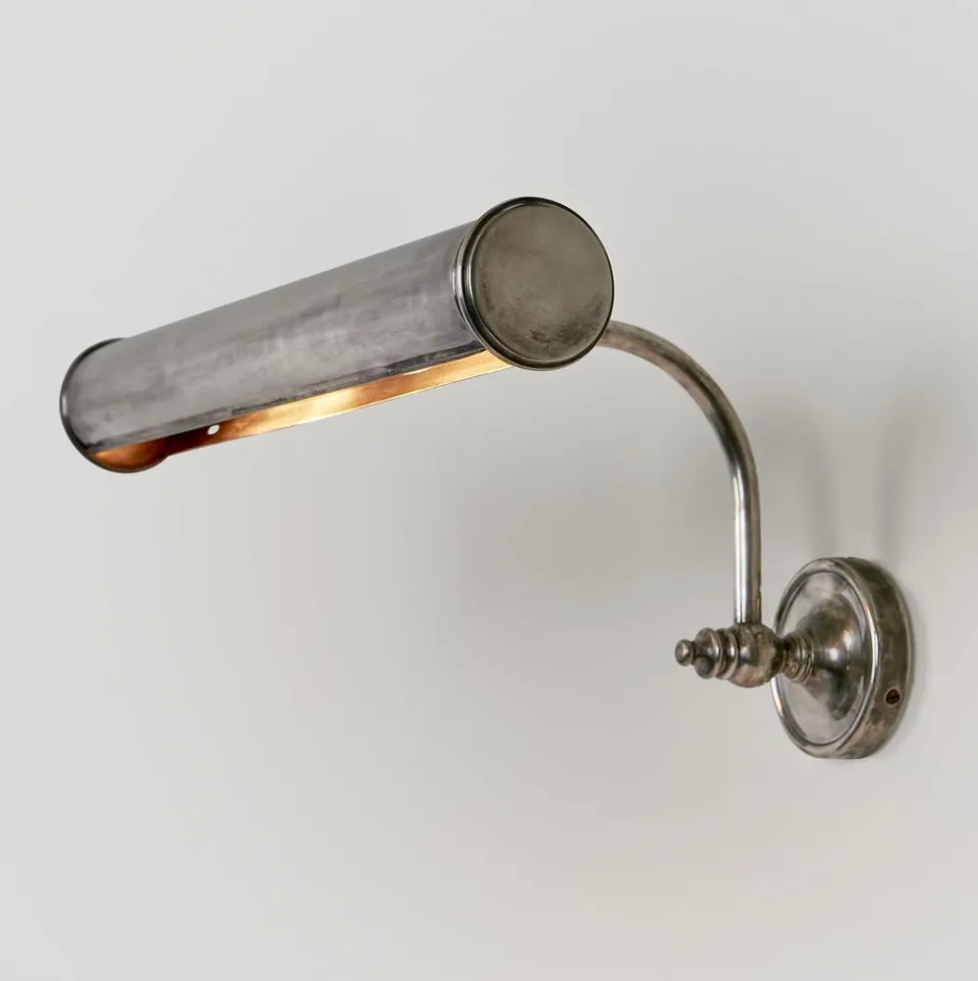 Wall-mounted metal lamp with adjustable arm on a light gray background
