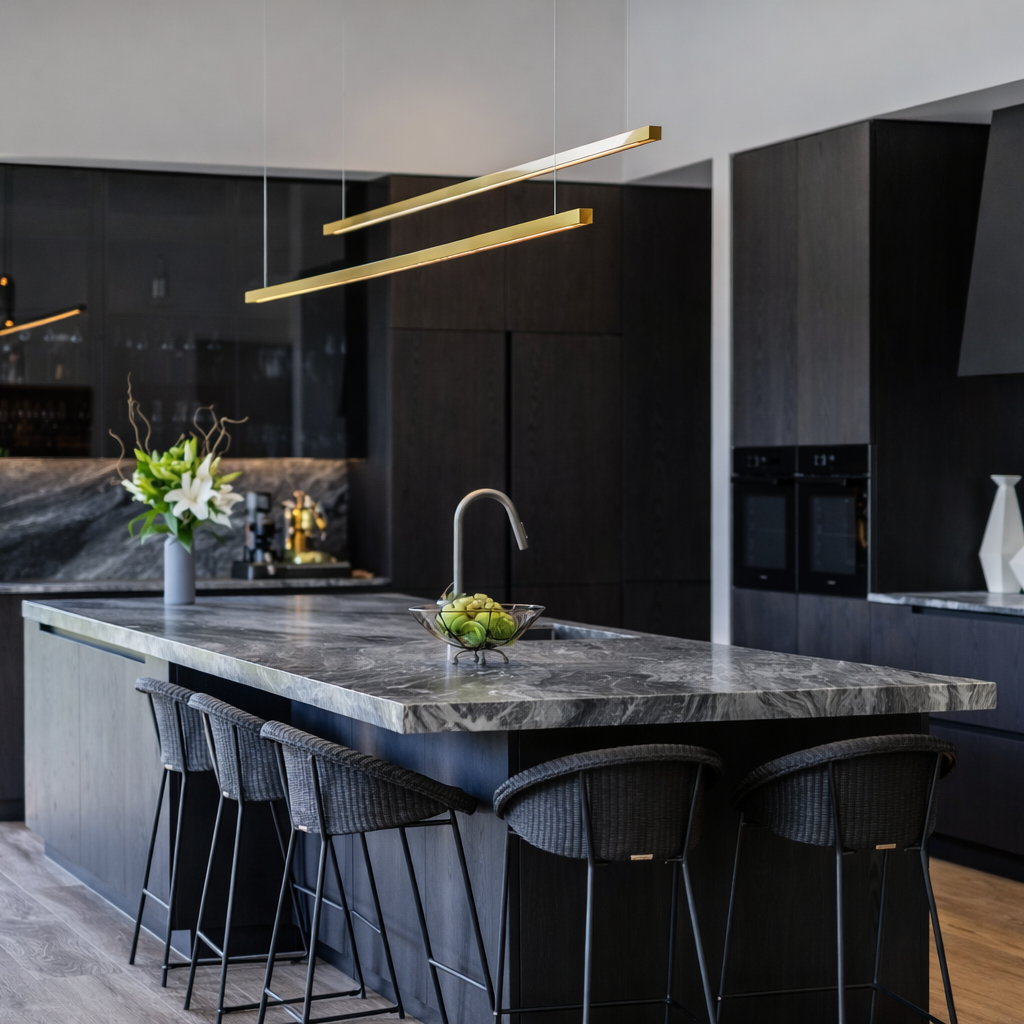 Modern kitchen with brass linear lights, black cabinets, marble island, and pendant lights.