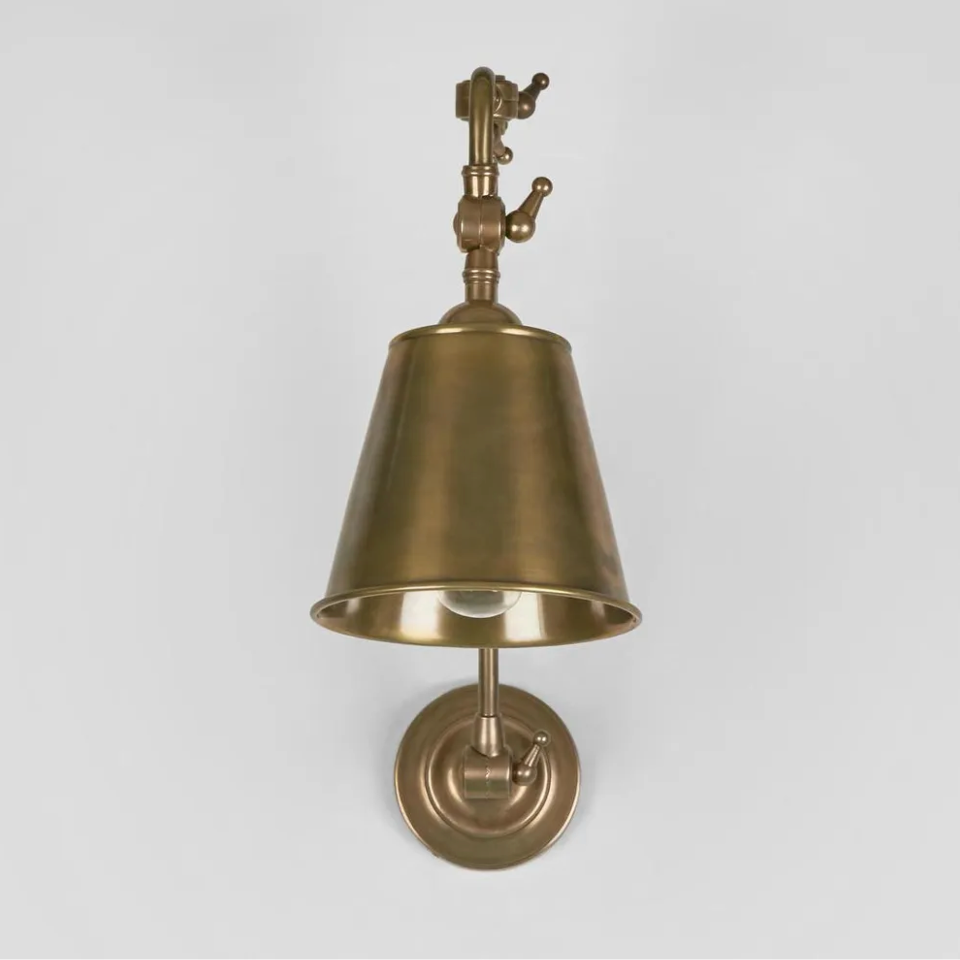 Brass wall-mounted light fixture on a gray background