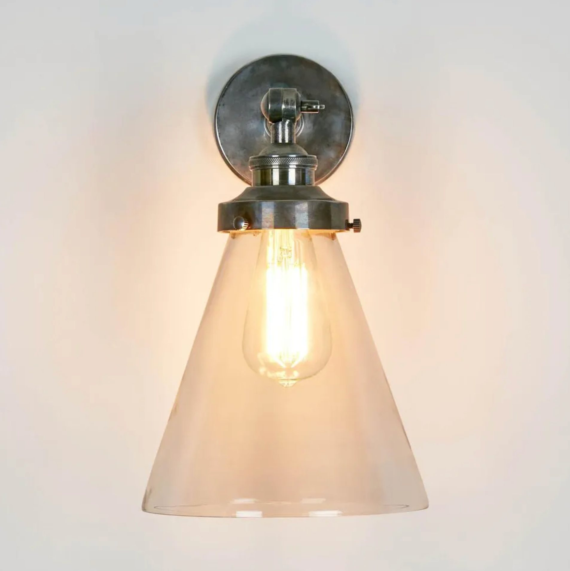 Wall-mounted light fixture with glass shade on a plain background