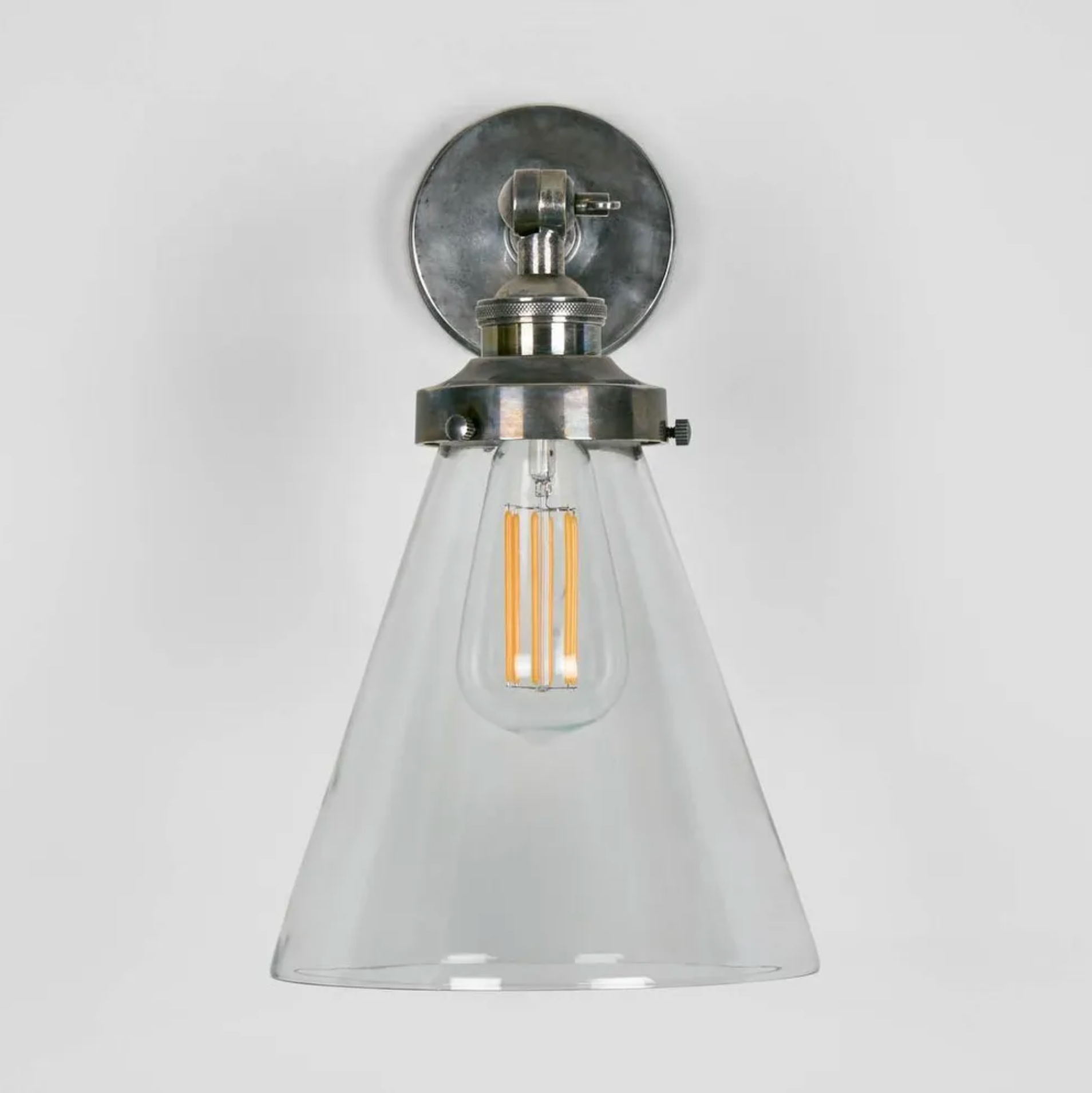 Antique slver Wall-mounted light fixture with clear glass shade and metallic base on a white background