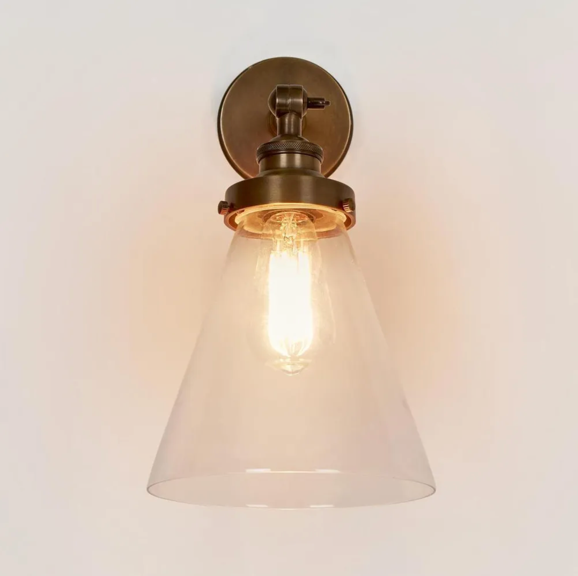 Vintage-style antique brass wall light fixture with glass shade on a plain background