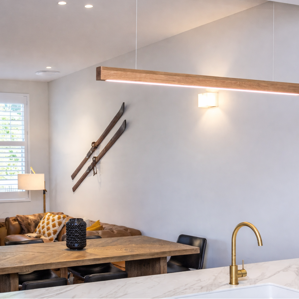 Modern kitchen with wooden pendant light, dining table, and sink.