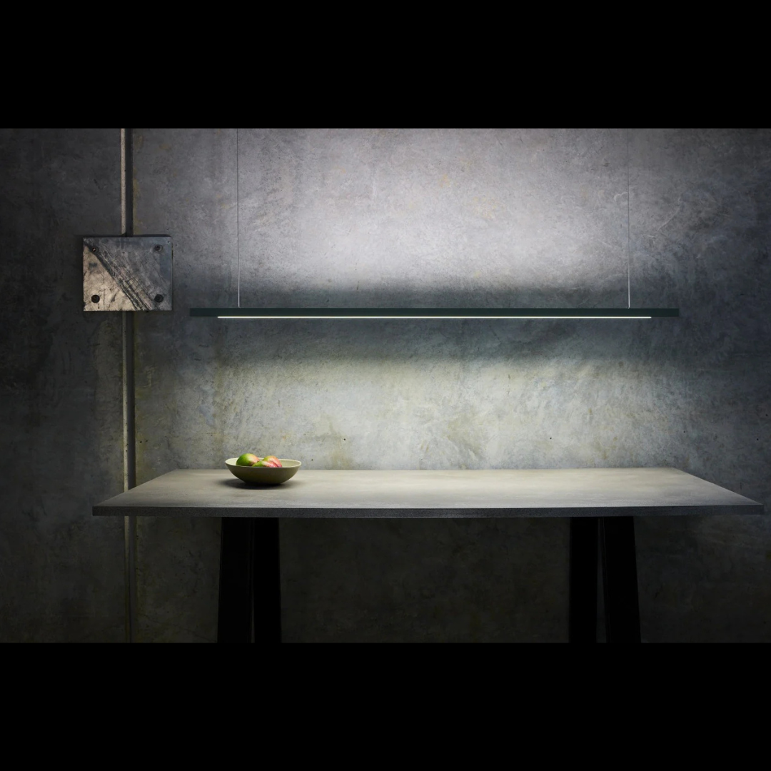 Modern kitchen setup with a bowl of fruit on a table against a dark wall.