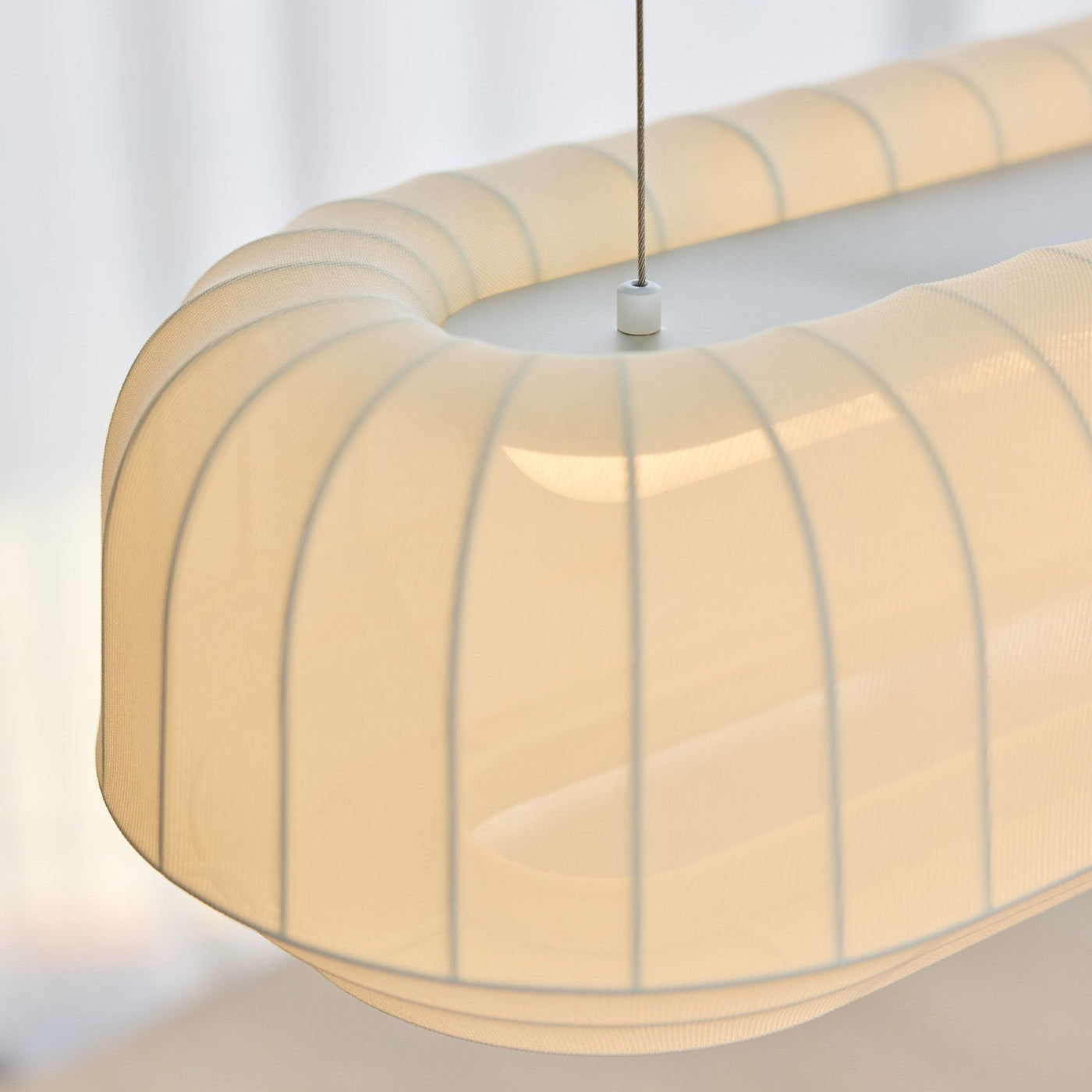 Beige pendant light with a ribbed design against a neutral background