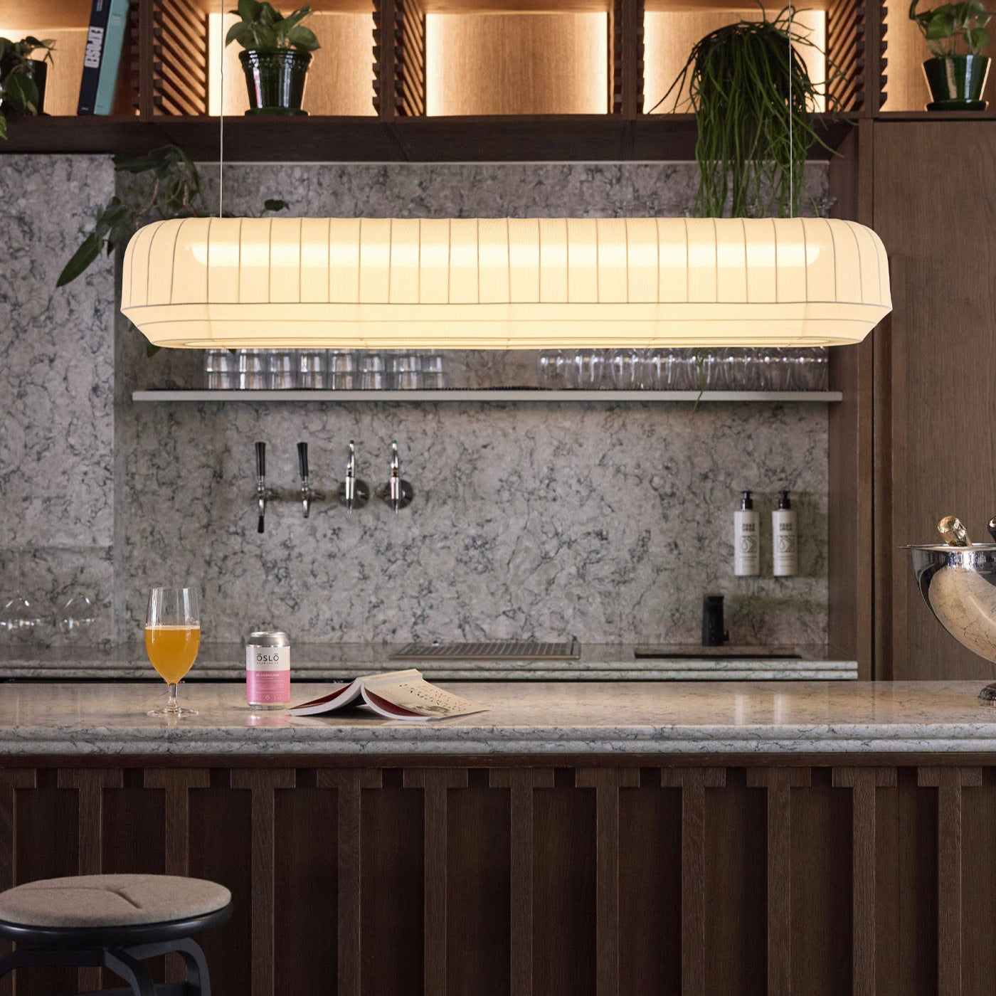 Modern bar setting with a pendant light, drinks, and a magazine.