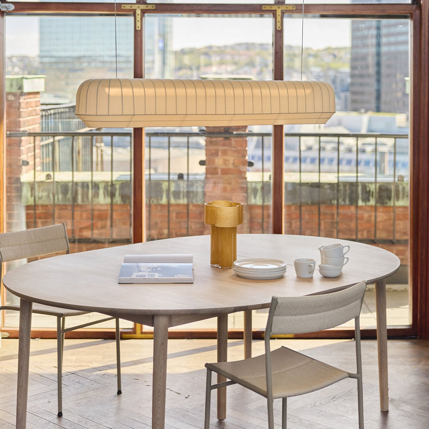 Dining table set with chairs in a modern room with large linear pendant.