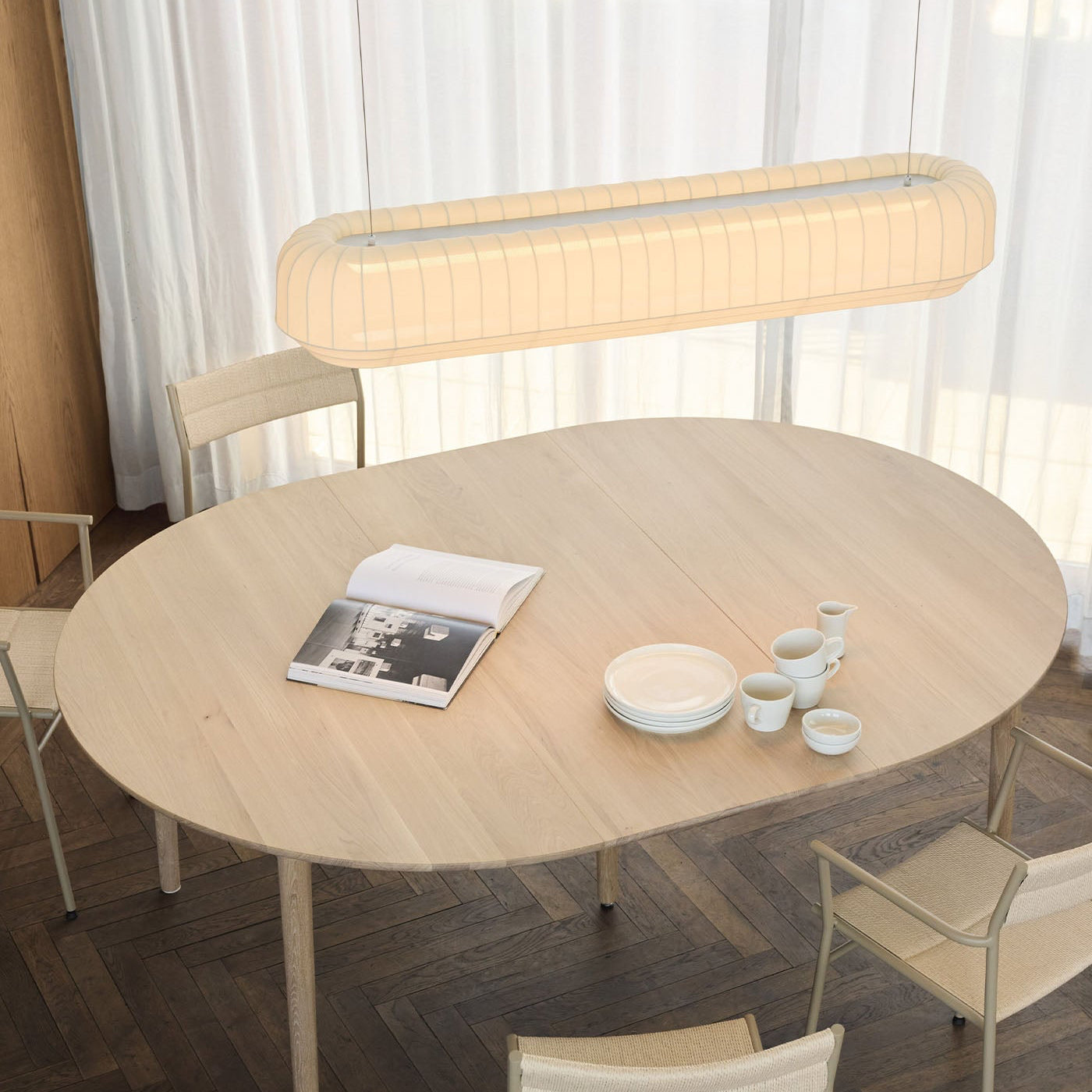 Dining area with a round wooden table, chairs, and a modern pendant light.