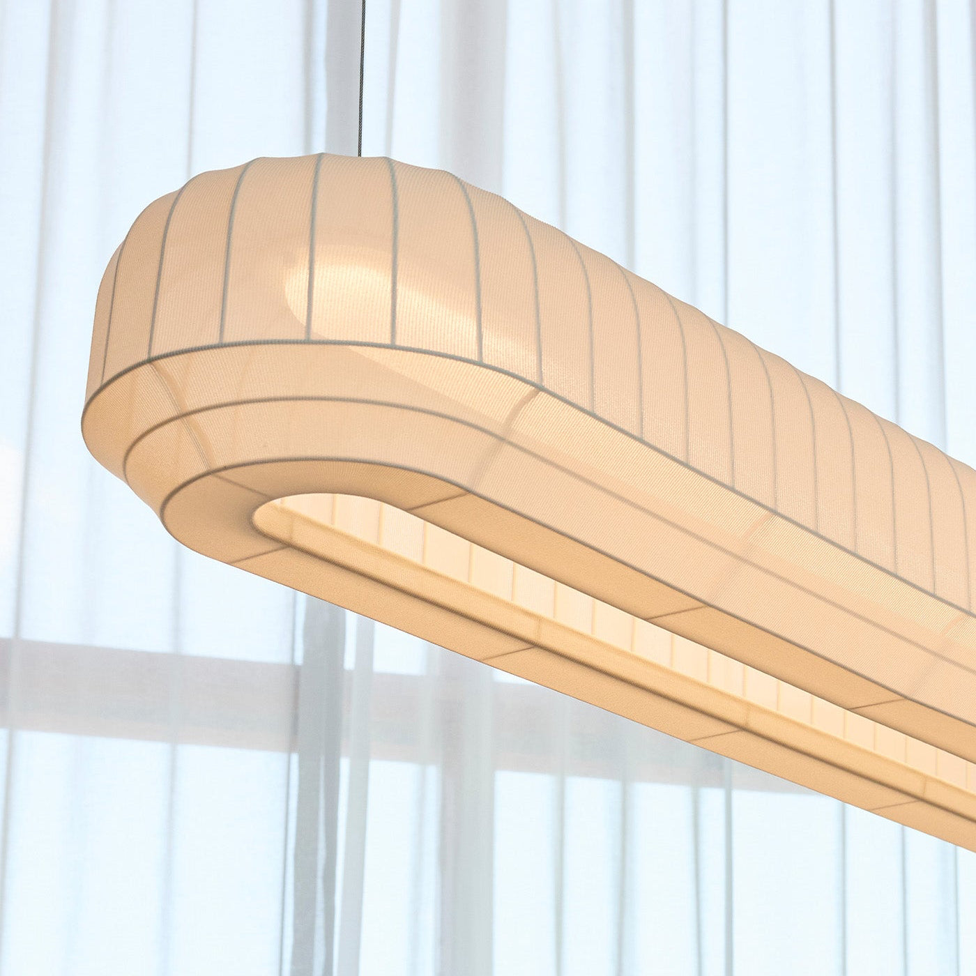 Fabric linear pendant light fixture with a white curtain background
