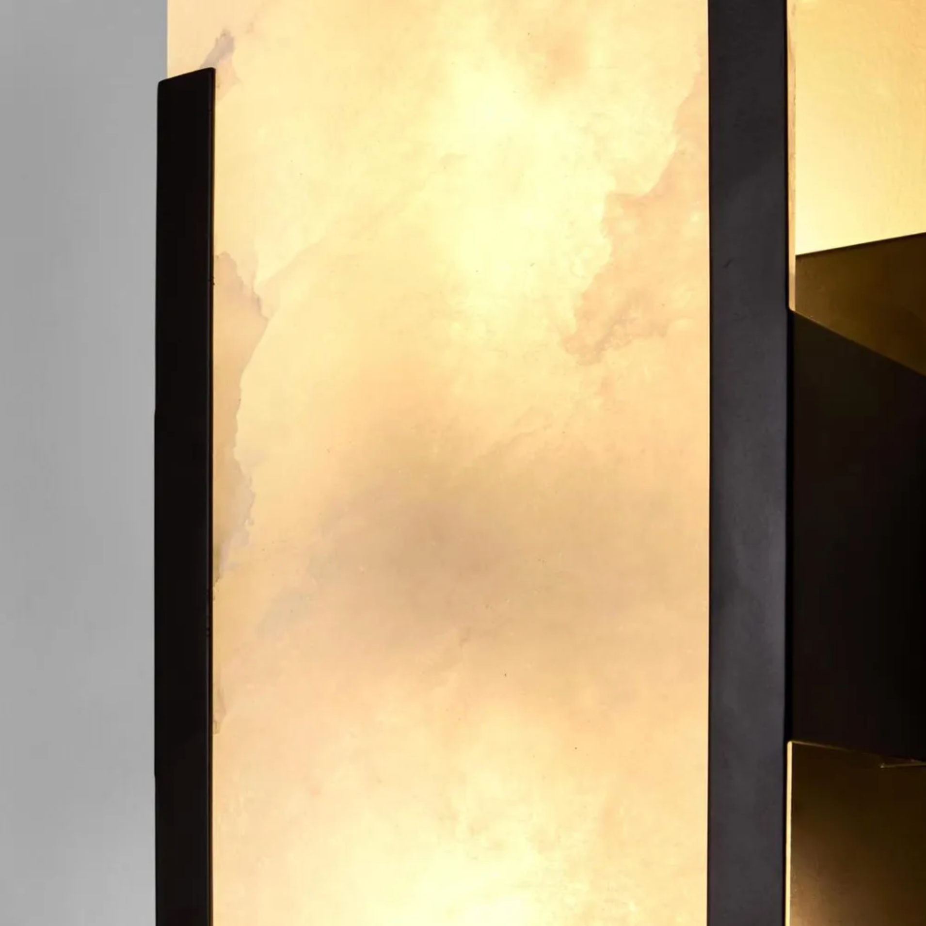 Wall-mounted light fixture with a textured marble shade and black frame.