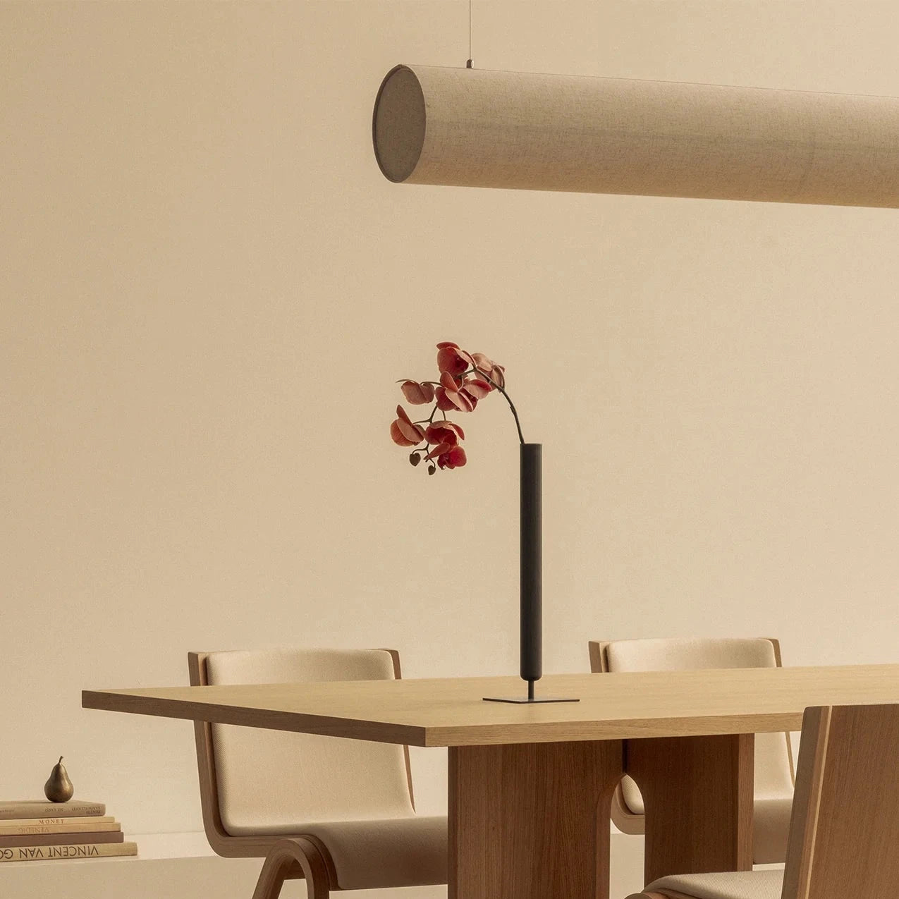Modern dining room with wooden table and chairs, featuring a minimalistic light fixture.