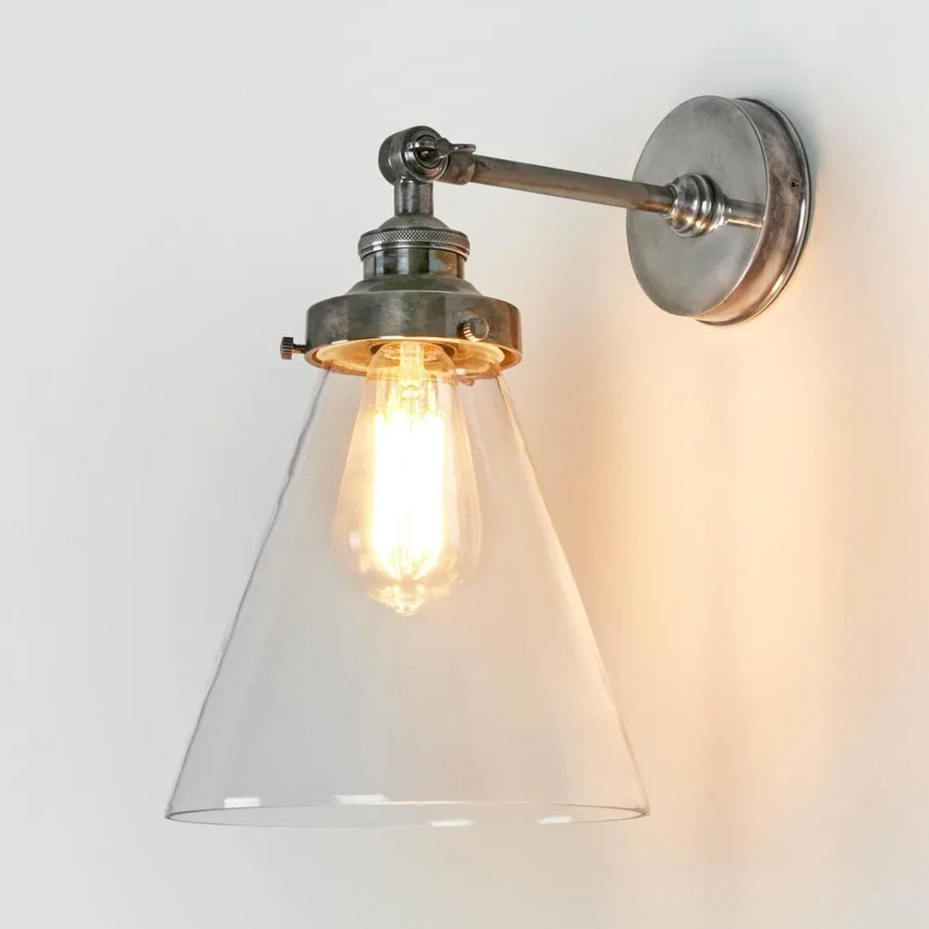 Wall-mounted light fixture with glass shade and visible bulb on a white background