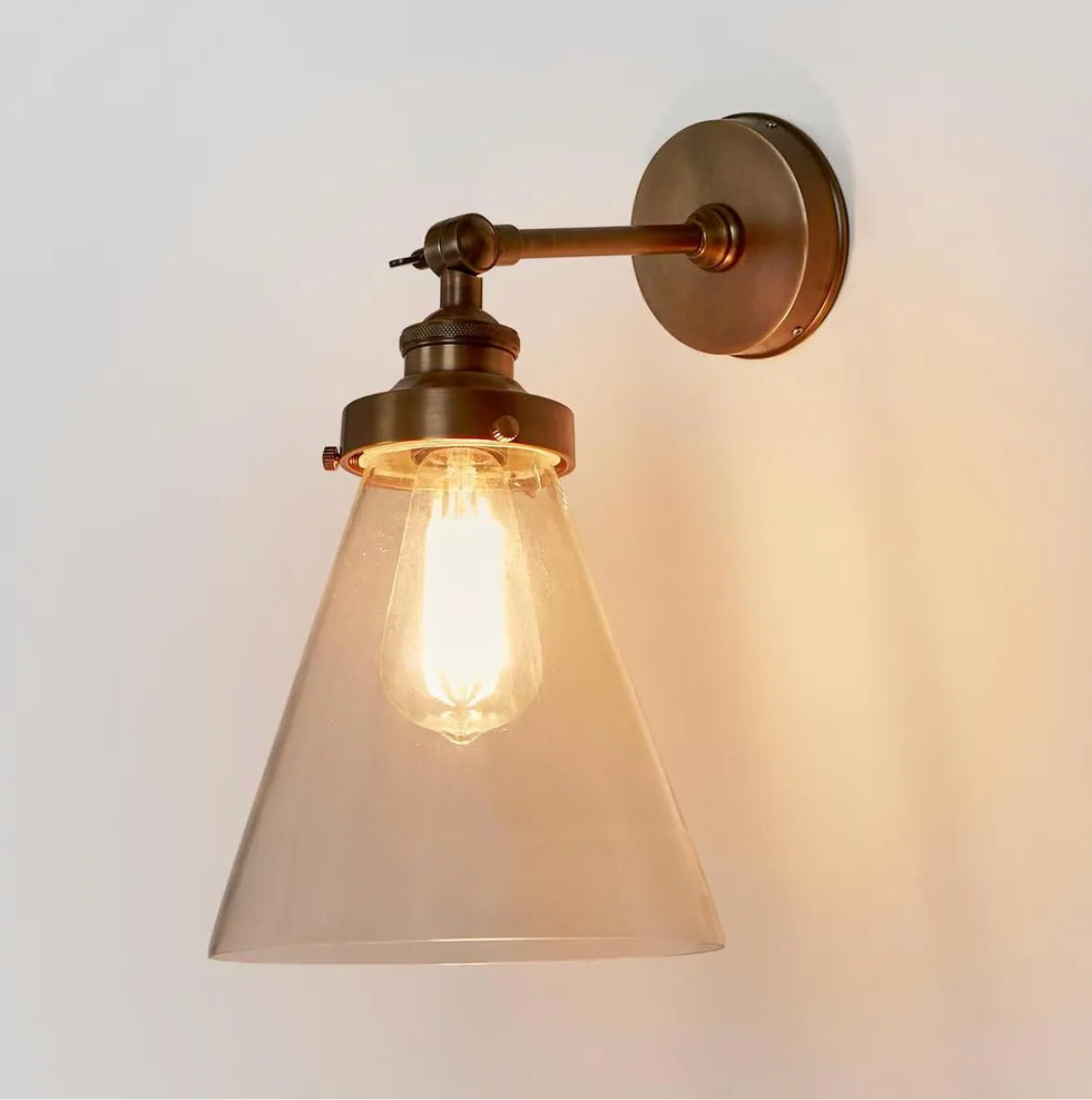 Vintage-style wall light fixture with glass shade on a plain background