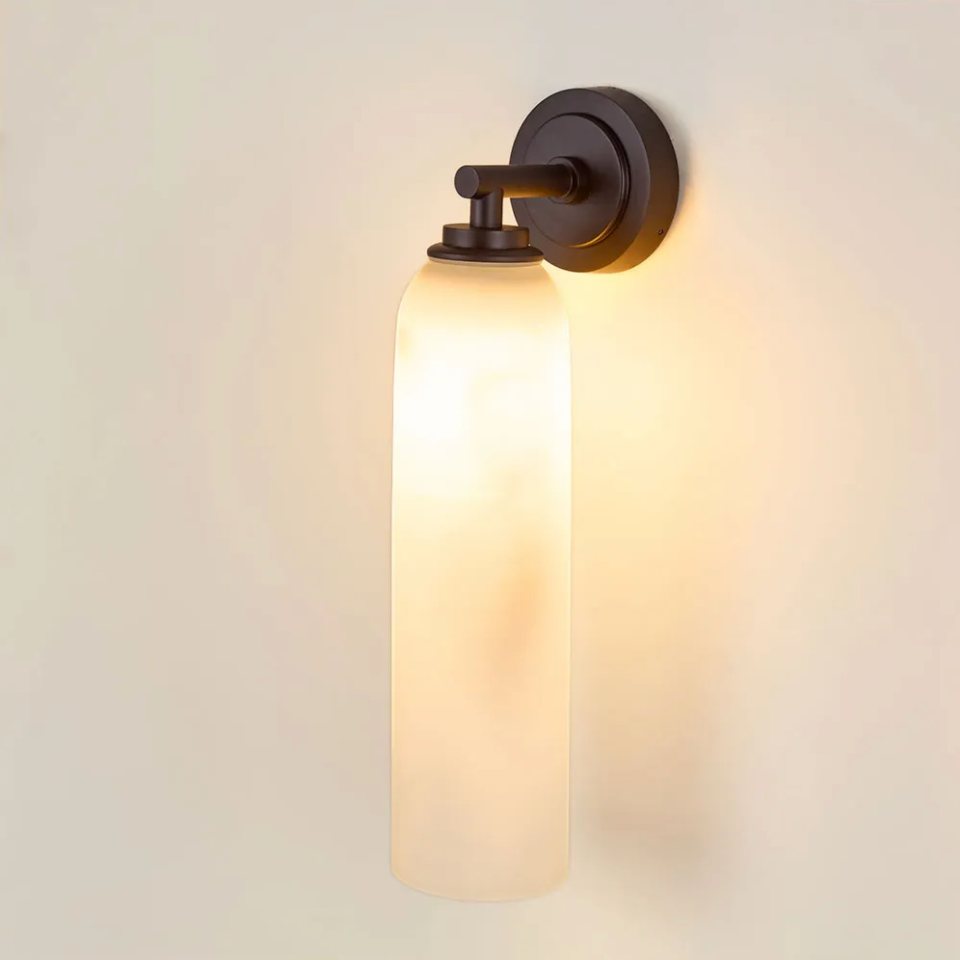Wall-mounted light fixture with glass shade on a neutral wall