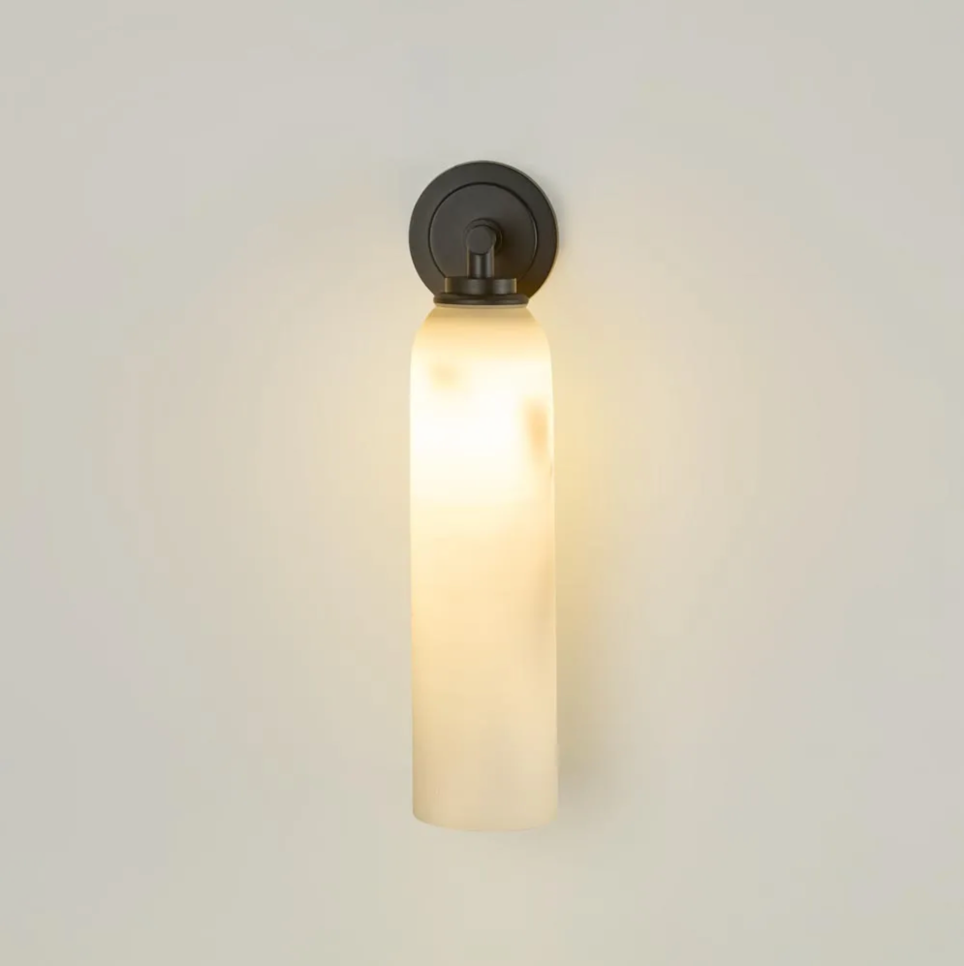 Wall-mounted light fixture with a cylindrical glass shade on a plain background