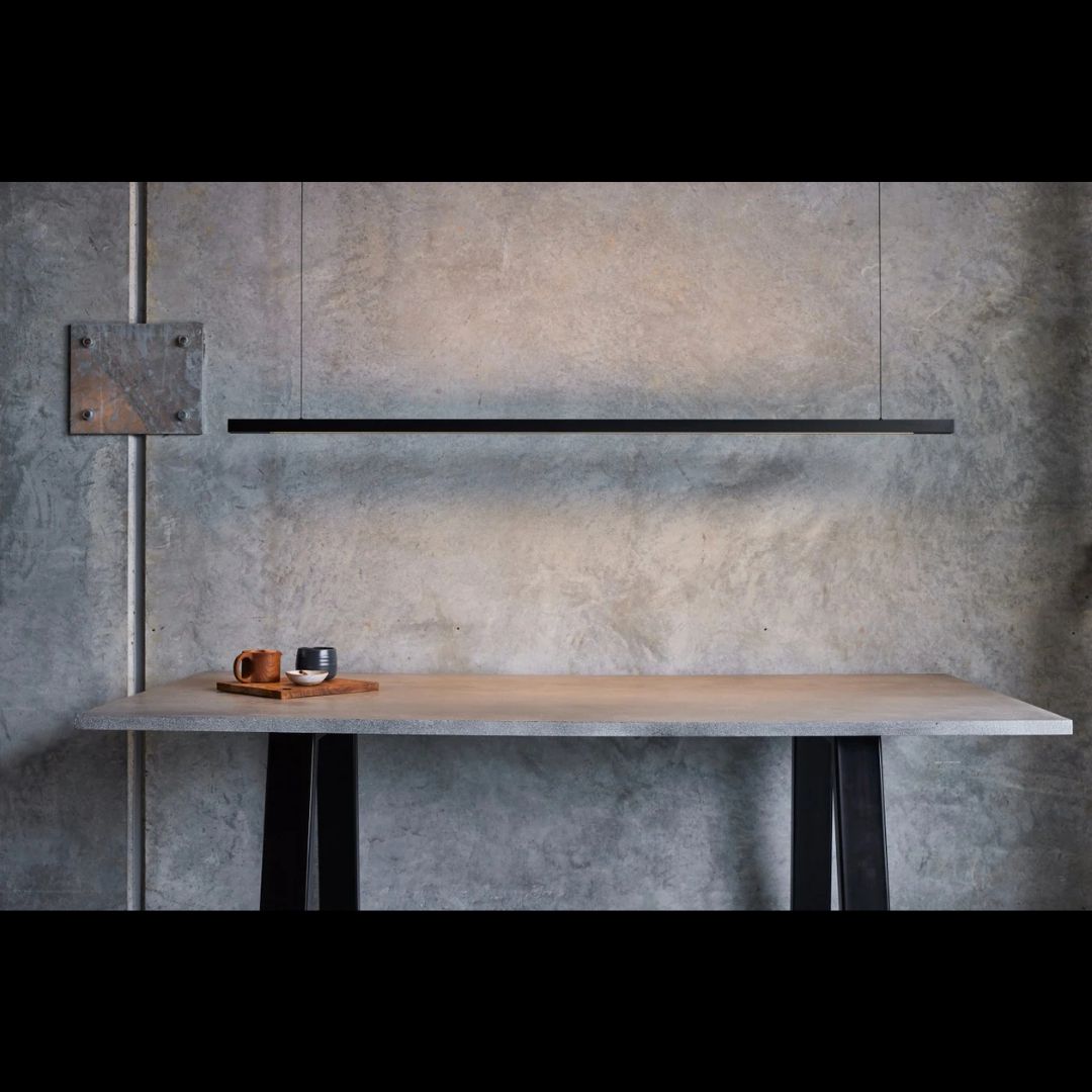 Black linear light countertop against a textured wall.