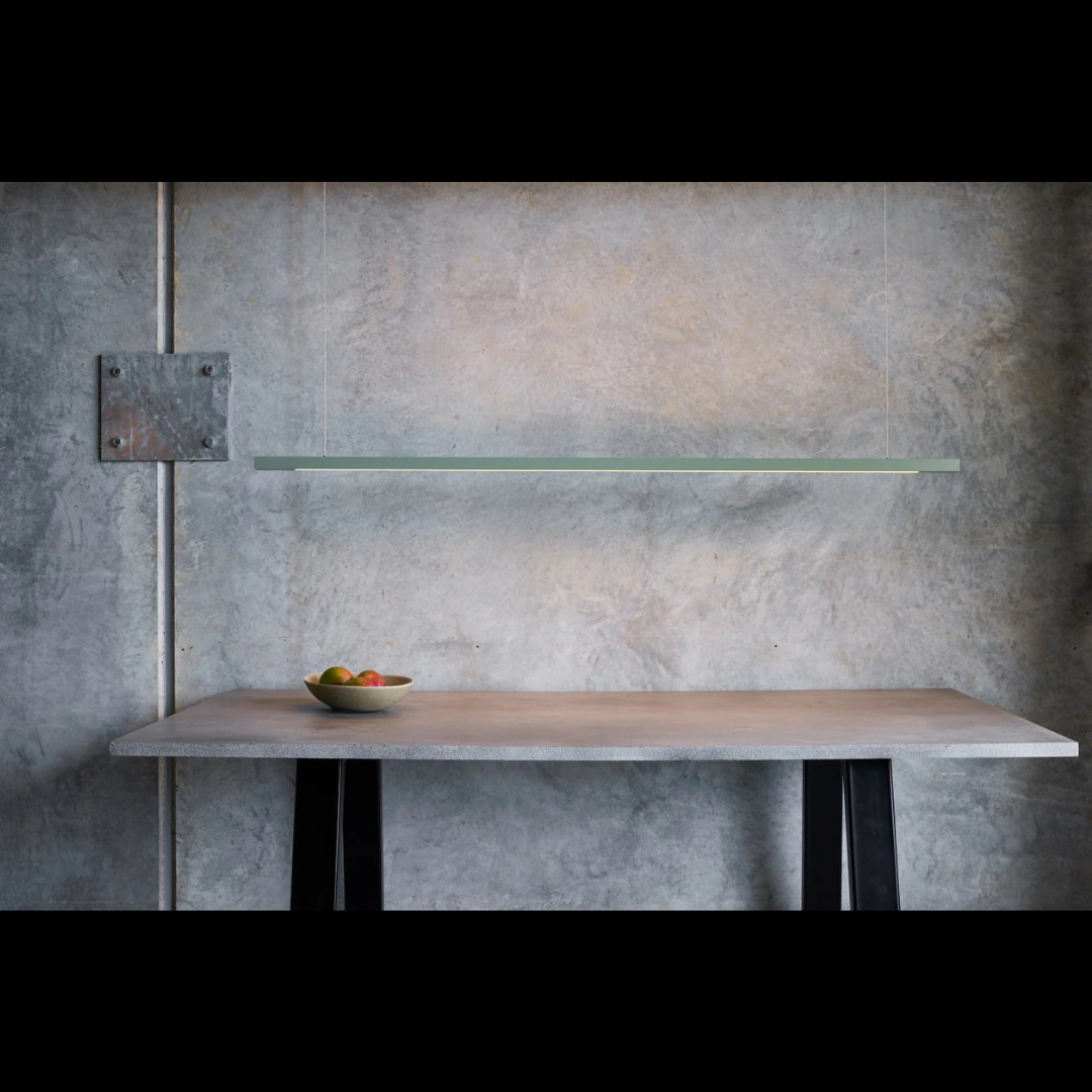 Modern kitchen setup with a concrete wall, wooden table, and fruit bowl.