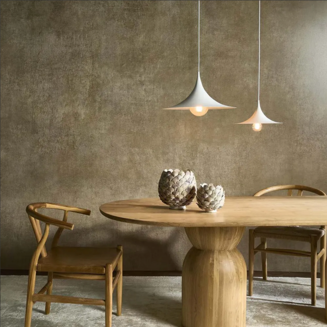 Dining area with wooden table and chairs, featuring two pendant lights against a textured wall.